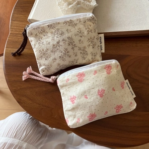 Close-up of floral cotton coin purses with metal zippers and woven fringe tassels