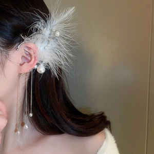 Detail of elegant feather ear cuff with faux pearls and long metal fringe tassels