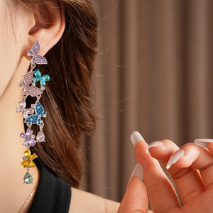 Close-up of vintage butterfly tassel earrings with colorful rhinestones on a model