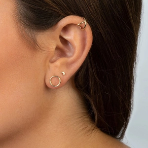Close-up of a minimalist gold moon stud earring and cuff set on a woman's ear