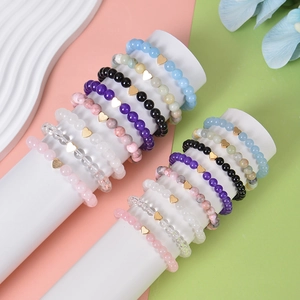 Natural stone bead bracelets set with gold heart pendants on elegant display stand