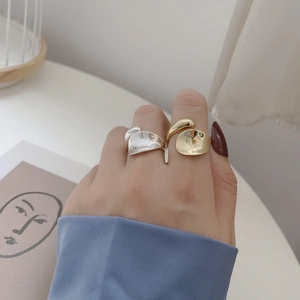 Close-up of minimalist gold and silver teardrop rings on model fingers