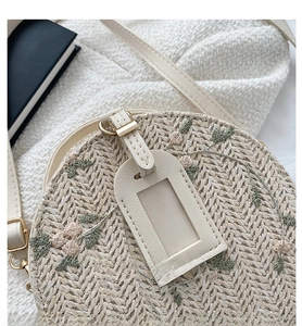 Close-up of circular straw bag featuring elegant floral embroidery and leather strap