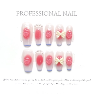 Detail of handmade press-on nails with 3D pink hearts, pearls and cream ribbon bows