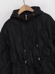Detailed shot of wave-quilted jacket fabric with luxury golden zipper and waist drawstring