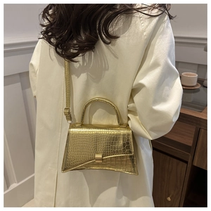 Detail of the golden crocodile embossed hourglass bag with metallic finish and top handle
