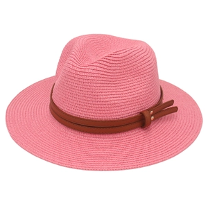 Detail of pink woven straw fedora featuring a brown leather band and metal rivets
