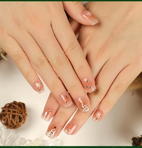 Detail of short square Christmas nails with snowflake patterns and star rhinestones