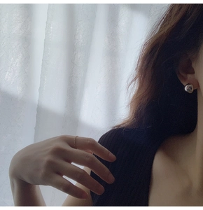 Close-up of minimalist silver spherical stud earring and gold beaded ring on model