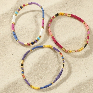 Three-piece colorful TILA enamel bead elastic bracelets set on a sandy beach