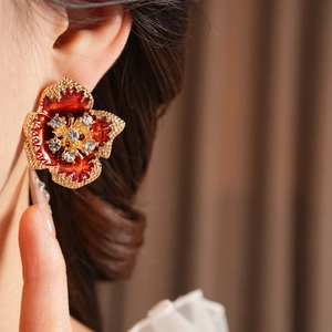 Macro detail of vintage floral earring with red enamel and crystals on model ear