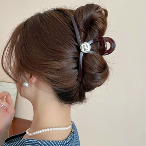 Macro view of vintage brown acrylic hair claw clip with metallic logo on French updo