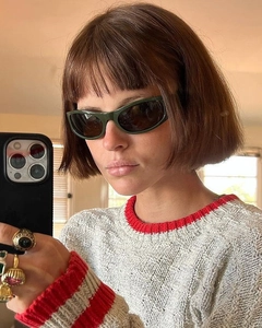 Detail of dark green narrow cat-eye sunglasses with gold rings and knit sweater
