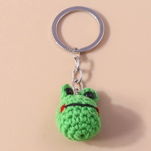 Close-up of handmade crochet green frog keychain with metal ring and bead eyes