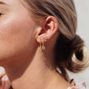 Gold North Star and snake charm hoop earring set worn by a model in natural light