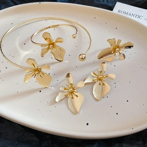 Macro view of gold flower jewelry set with necklace, bracelet and ring on tray