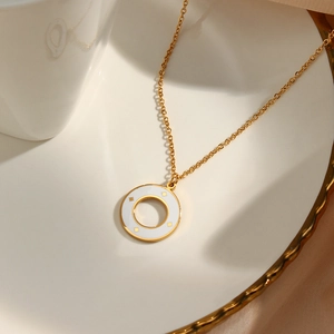Detailed macro view of a gold necklace featuring a white enamel ring pendant with star patterns