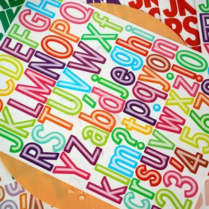 Close-up of waterproof 1.5-inch rainbow alphabet and number stickers with water droplets