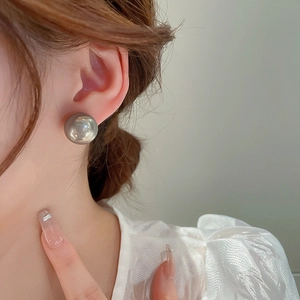 Gros plan d'un mannequin portant une boucle d'oreille perle grise sur le lobe