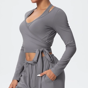 Detail of gray wrap-style long sleeve yoga top with side bow tie and athletic pants
