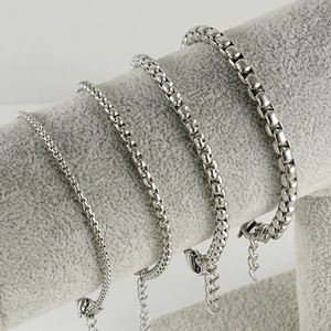 Silver stainless steel box chain bracelets in four widths on a gray jewelry display stand