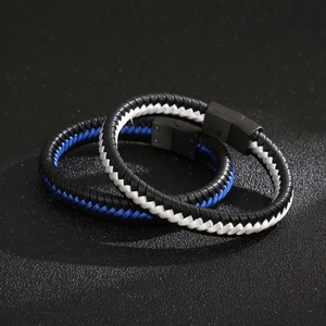 Detail of woven leather bracelets with black metal magnetic clasps on textured background