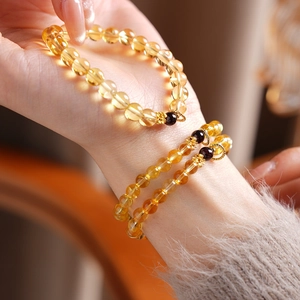 Detail view of natural citrine and garnet flower bracelet with golden floral pendant