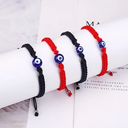Detail of red and black braided bracelets featuring the blue evil eye bead centerpiece