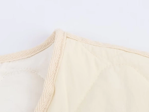 Close-up of beige quilted jacket collar with herringbone ribbon trim and fine stitching