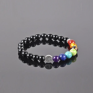 7 Chakra stone tree of life bracelet with black beads on a reflective grey surface