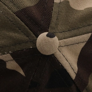 Detailed macro view of camo baseball cap crown button and durable twill cotton stitching