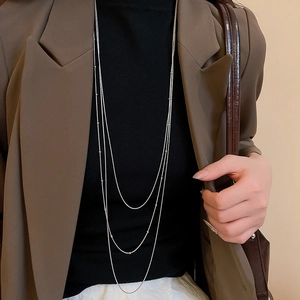 Close-up of three-layered silver snake chain necklace on model wearing black turtleneck