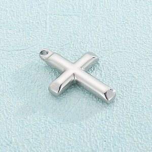Detailed close-up of a polished silver stainless steel cross pendant on blue background