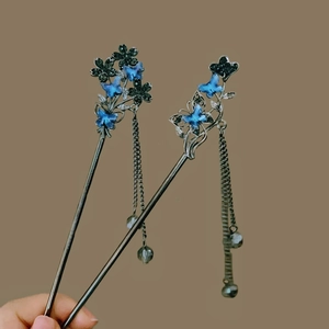 Detailed view of blue butterfly hairpins with silver metallic tassels and floral accents