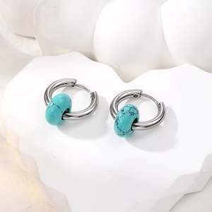 Detail view of silver hoop earrings with blue turquoise marble beads on white blocks
