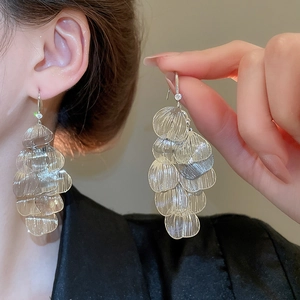 Macro detail of layered silver petal tassel earrings with textured metallic finish