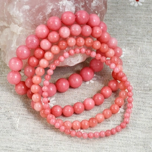 Detailed macro view of pink rhodochrosite beaded bracelets in various sizes on stone