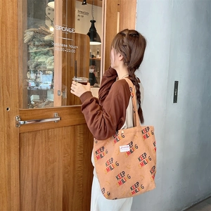 Close-up of light brown corduroy tote bag with Keep Smiling print in an outdoor setting