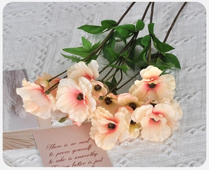 Close-up of artificial poppy petals with pink and cream gradients on white lace