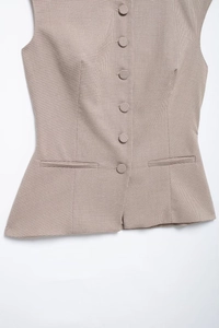 Detail shot of vintage plaid vest with front buttons and waist welt pockets on white background