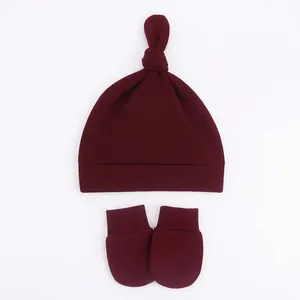 Detail view of wine red knotted baby beanie and anti-scratch mittens set in soft cotton