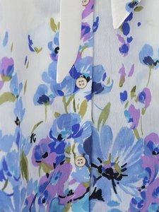 Close-up of floral print blouse featuring a bow collar and gold-trimmed white buttons
