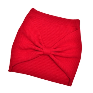 Detail of red ribbed knit headband featuring a stylish knotted bow design and soft wool texture
