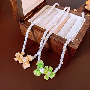 Gold plated pearl necklace with vintage floral crystal pendants on a wooden box