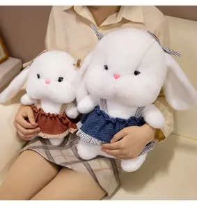 Detailed close-up of soft white plush bunny toys in knit dresses showing fabric texture