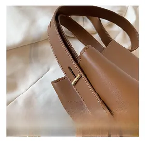 Detail of adjustable leather shoulder strap with premium golden metal buckle on brown bag