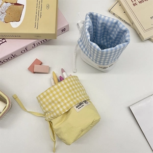 Detail of checkered drawstring stationery bags in yellow and blue colors for desk storage