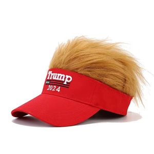 Detail view of red baseball cap featuring gold synthetic hair and Trump 2024 embroidery