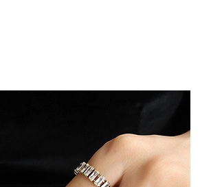 Macro shot of gold-plated ring with rectangular white zircons on black satin