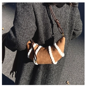 Detail of caramel suede croissant bag with faux shearling stripes and leather strap